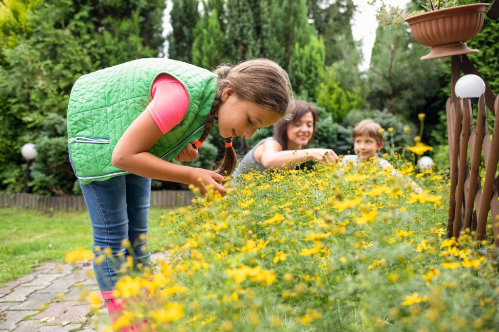 Little girl with family in backyard garden take care of plants together