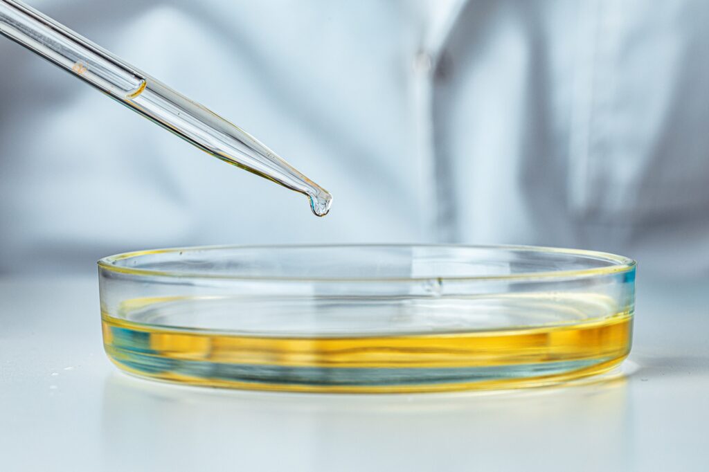 Petri dish and pipette with dropping liquid close up