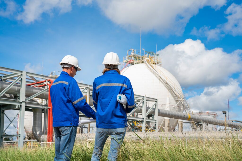 Team Petroleum chemical engineer discussion about blueprint drawings inside Oil Refinery Gas