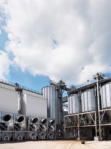 Agricultural Silos. Building Exterior. Storage and drying of grains, wheat, corn, soy, sunflower against the blue sky with white clouds.
